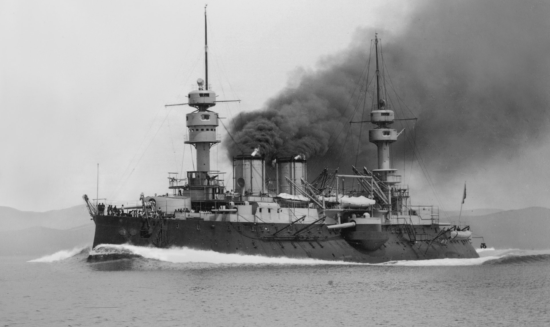 Black and white 4K Ultra HD wallpaper of the French Navy battleship Jauréguiberry steaming with smoke billowing from its funnels.