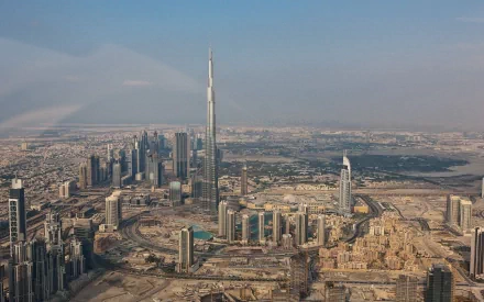HD wallpaper showing Dubai's skyline dominated by tall skyscrapers, including the iconic Burj Khalifa, with a sprawling urban landscape in the background. Man-made marvels and modern architecture.