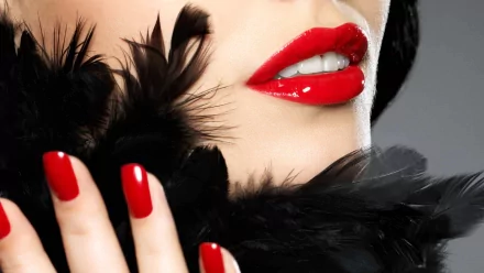 A striking HD desktop wallpaper featuring a close-up of a woman's lips adorned in bold red lipstick, complemented by perfectly manicured red nails and a touch of black feathers.