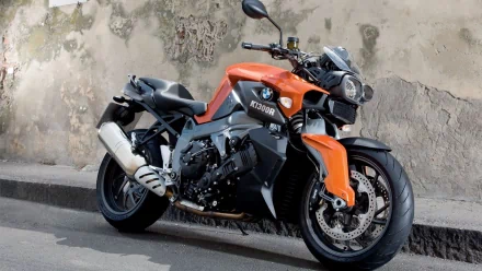 HD PC desktop wallpaper and background: orange-and-black BMW K1300R motorcycle parked by a weathered wall, close-up view of the vehicle.
