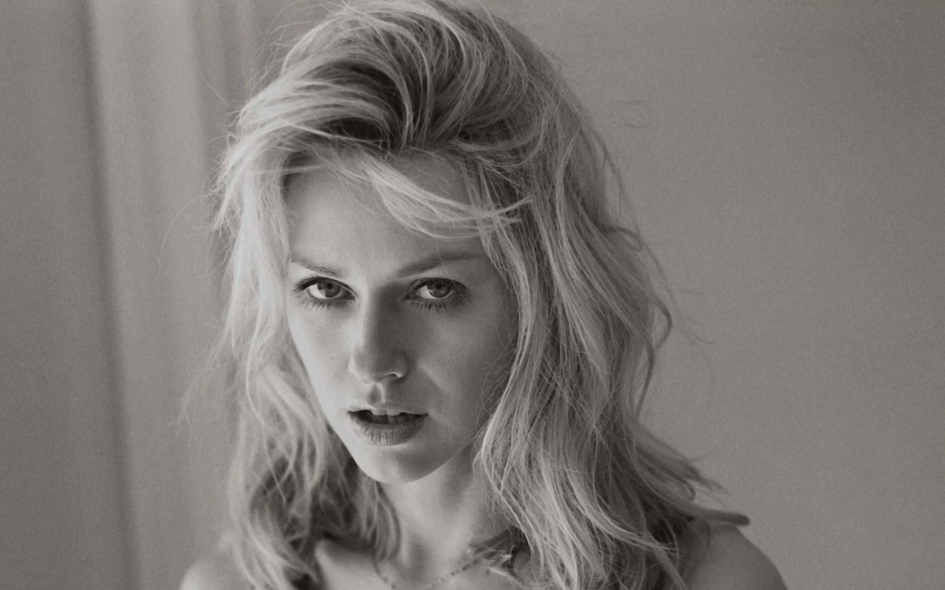 Black and white HD desktop wallpaper featuring a close-up portrait of celebrity Naomi Watts with tousled hair and an intense gaze.