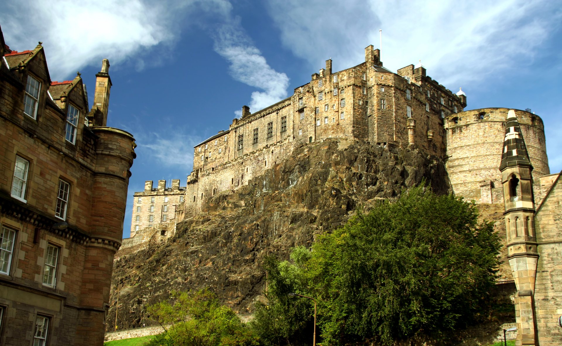 HD desktop wallpaper featuring the man-made Edinburgh Castle perched on a rocky hill under a partly cloudy sky.