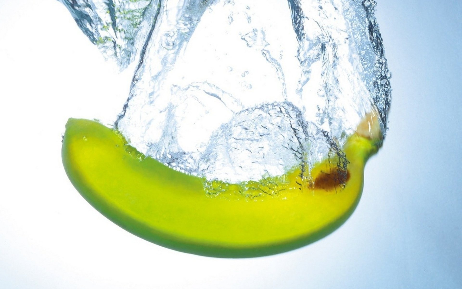 HD desktop wallpaper showing a banana submerged in clear water with splashes, highlighting the freshness of the fruit against a bright background.