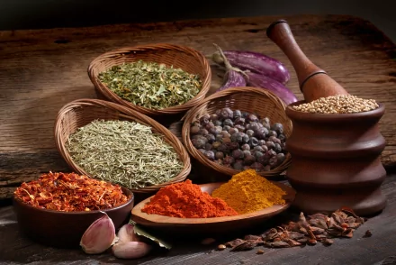 A vibrant display of herbs and spices in woven baskets, featuring colorful powders and whole spices, set against a rustic wooden backdrop. 4K Ultra HD quality wallpaper.