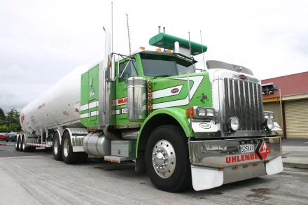 HD desktop wallpaper featuring a green Peterbilt semi-truck with a large tanker trailer parked on a concrete surface.