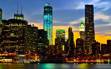 HD desktop wallpaper of Manhattan, New York skyline at sunset featuring illuminated buildings and the One World Trade Center.