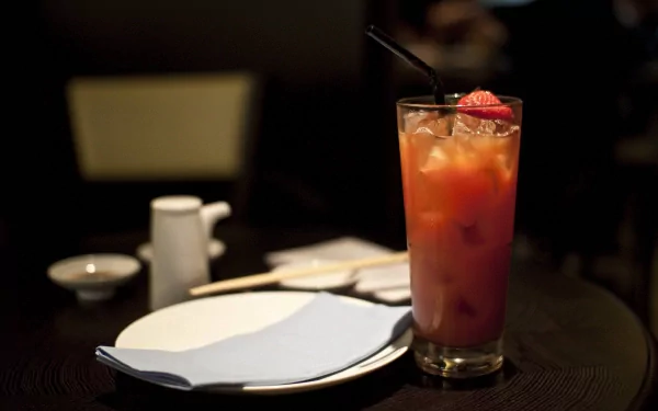 4K Ultra HD PC desktop wallpaper featuring a vibrant cocktail with ice and a strawberry garnish on a dark table set with plates and chopsticks.