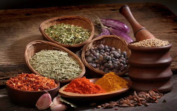 A vibrant display of herbs and spices in woven baskets, featuring colorful powders and whole spices, set against a rustic wooden backdrop. 4K Ultra HD quality wallpaper.