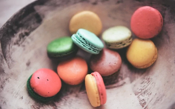 A delightful assortment of colorful macarons arranged in a rustic bowl, showcasing various flavors. This HD image captures the essence of sweet chocolate desserts.