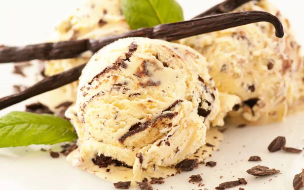 Delicious vanilla ice cream with chocolate chunks, garnished with mint leaves and vanilla pods, captured in stunning 4K Ultra HD for a vibrant desktop wallpaper.