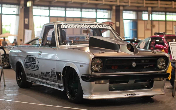 HD PC desktop wallpaper featuring a customized silver Datsun pickup truck displayed indoors at a car show.