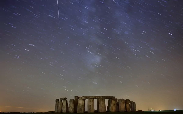 A stunning HD desktop wallpaper featuring Stonehenge set against a starry night sky, showcasing the ancient monument with celestial trails and a serene atmosphere.