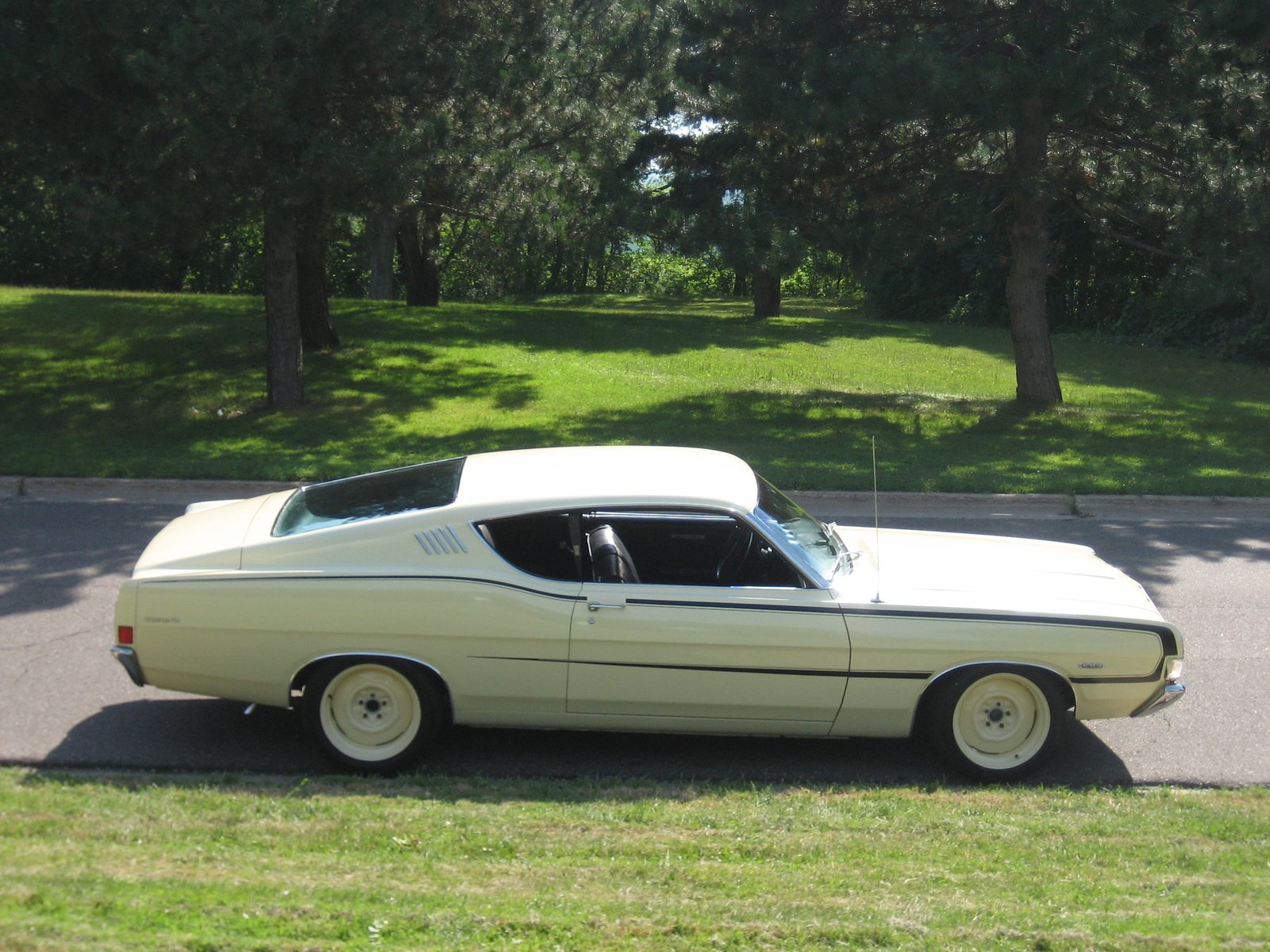 HD PC desktop wallpaper featuring a classic white Ford Torino GT parked on a street with green trees in the background.