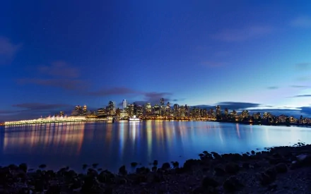 A stunning HD wallpaper featuring the Vancouver skyline at dusk, reflected in the calm waters, showcasing a blend of city lights and natural beauty.
