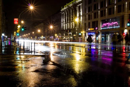 Nighttime city street captured in a time lapse style, reflecting colorful lights on wet pavement, presented as an HD PC desktop wallpaper and background.