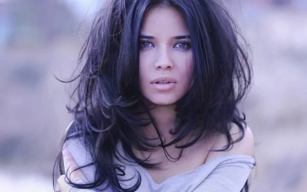 A sensual woman with long, tousled hair gazes intently at the viewer, creating a captivating atmosphere in this HD desktop wallpaper and background.