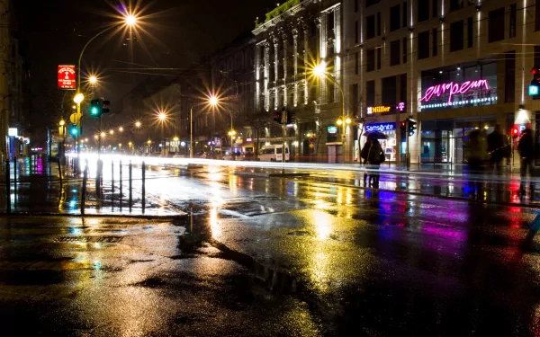 Nighttime city street captured in a time lapse style, reflecting colorful lights on wet pavement, presented as an HD PC desktop wallpaper and background.