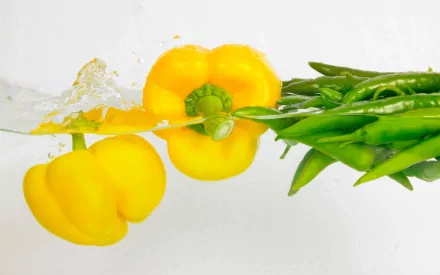 A vibrant HD desktop wallpaper featuring fresh yellow bell peppers and green beans splashing in water, highlighting the beauty of vegetables in a dynamic, artistic presentation.