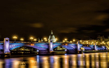 Night view of Southwark Bridge in London lit in blue, reflecting on the Thames — man-made structure captured as a 2K Quad HD PC desktop wallpaper and background.