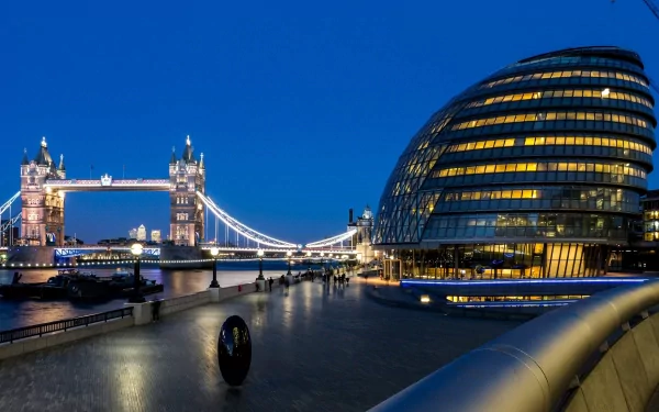 HD desktop wallpaper showcasing the iconic Tower Bridge and modern architecture along the River Thames in London, illuminated against a clear evening sky.