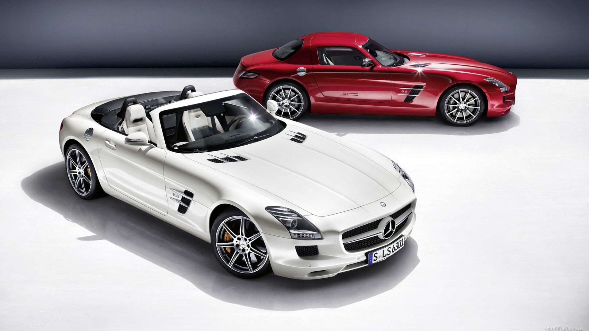 A striking white Mercedes-Benz SLS AMG convertible is showcased in the foreground, with a sleek red SLS AMG in the background, set against a clean, modern backdrop.