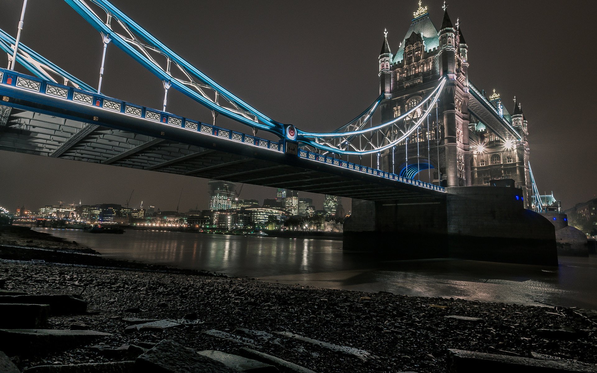 Night view of man-made Tower Bridge, blue-lit towers and suspension spans reflected in the Thames — HD PC desktop wallpaper and background, low-angle waterfront shot.
