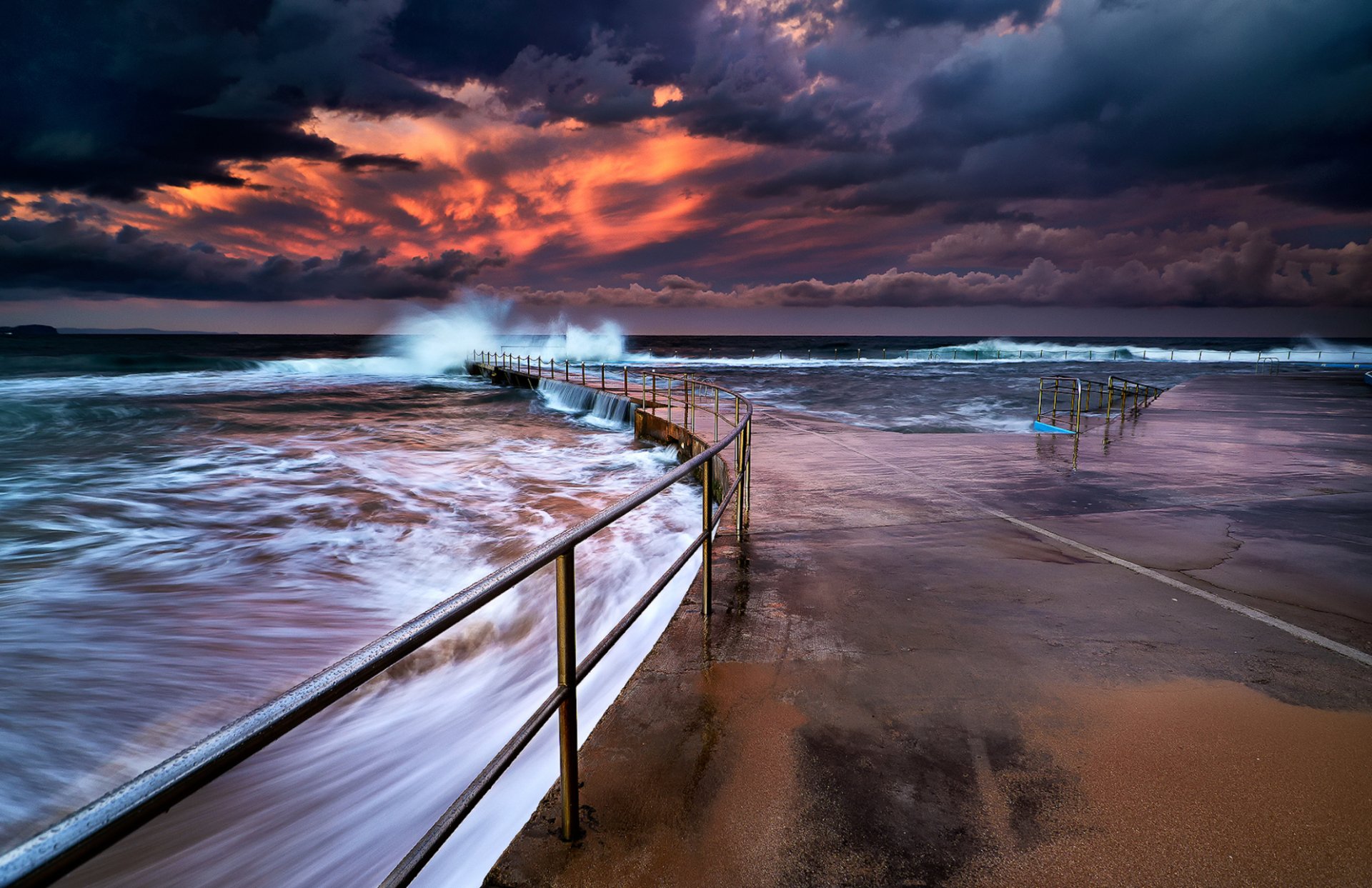 HD PC desktop wallpaper/background — ocean photography: stormy seascape at dusk with waves crashing over a curved railing and a flooded concrete platform.