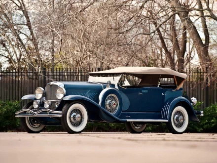 Classic blue Duesenberg Model J convertible parked outdoors, captured in high definition for a PC desktop wallpaper and background.