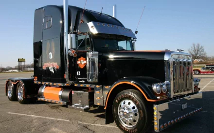 HD PC desktop wallpaper featuring a black and orange semi-truck parked under a clear blue sky, highlighting its detailed design and robust build.