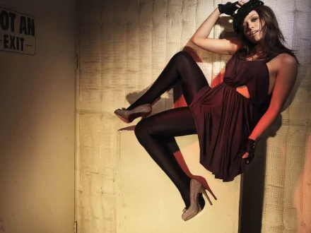 A stylish HD desktop wallpaper featuring celebrity Hilary Duff, showcasing her in a dramatic pose against a textured backdrop, wearing a chic outfit and heels.