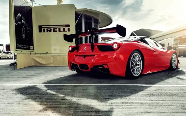 A vibrant red Ferrari Italia with a large rear wing parked by a Pirelli tent, captured as an HD PC desktop wallpaper and background.
