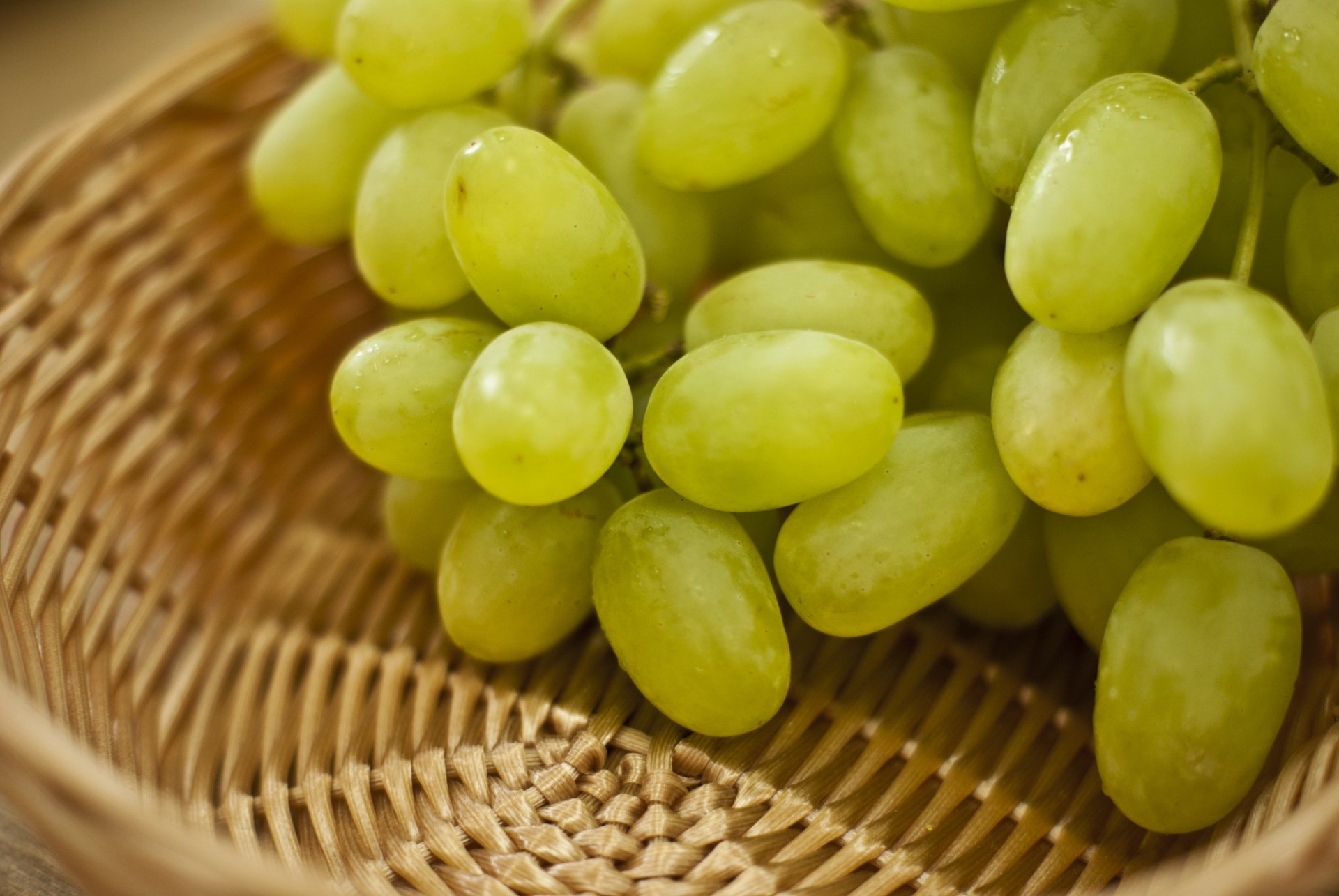 Close-up of fresh green grapes in a woven basket, captured in sharp detail as a vibrant 4K Ultra HD PC desktop wallpaper and background.