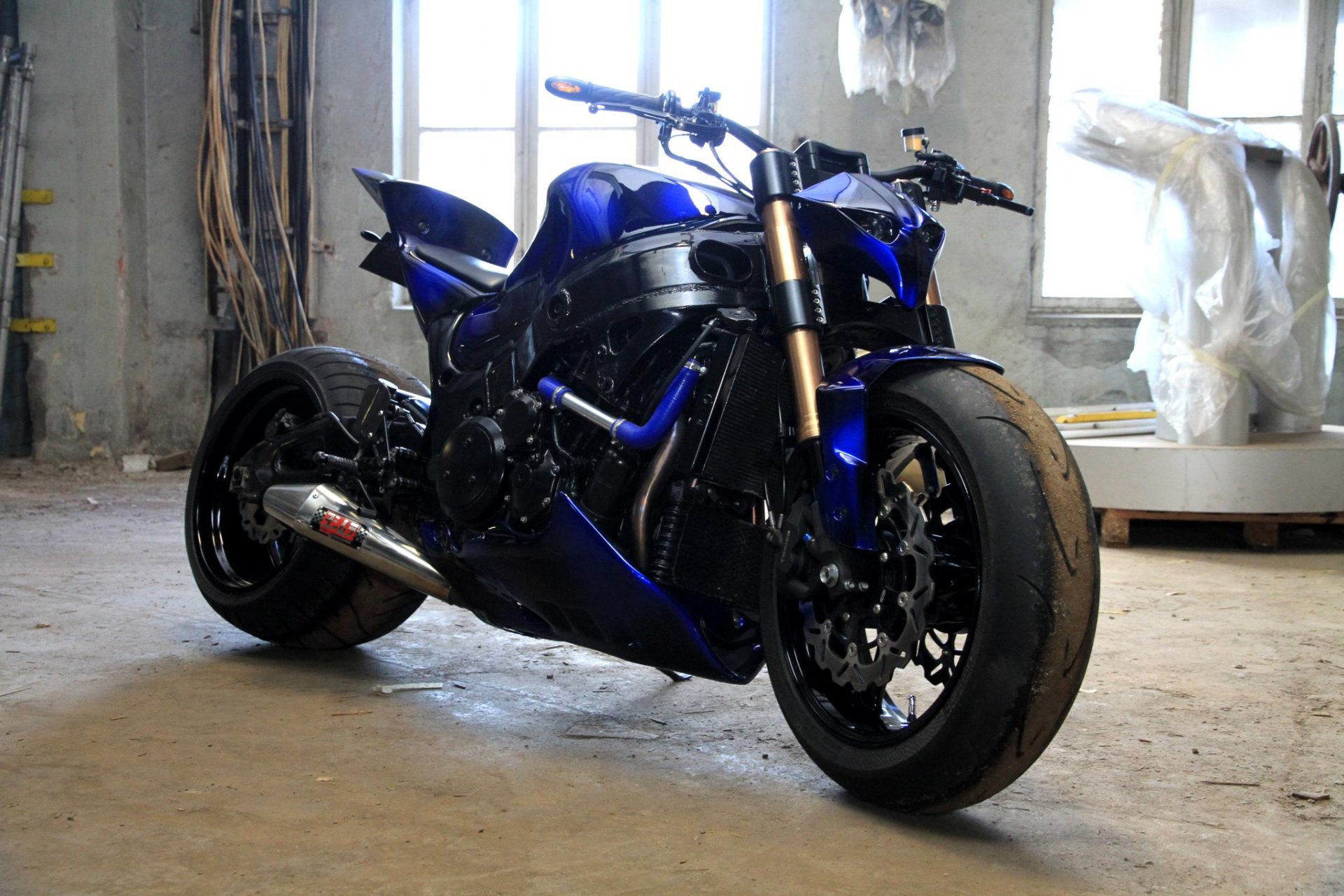 HD PC desktop wallpaper featuring a sleek, blue motorcycle parked indoors with natural light from windows illuminating its detailed design.