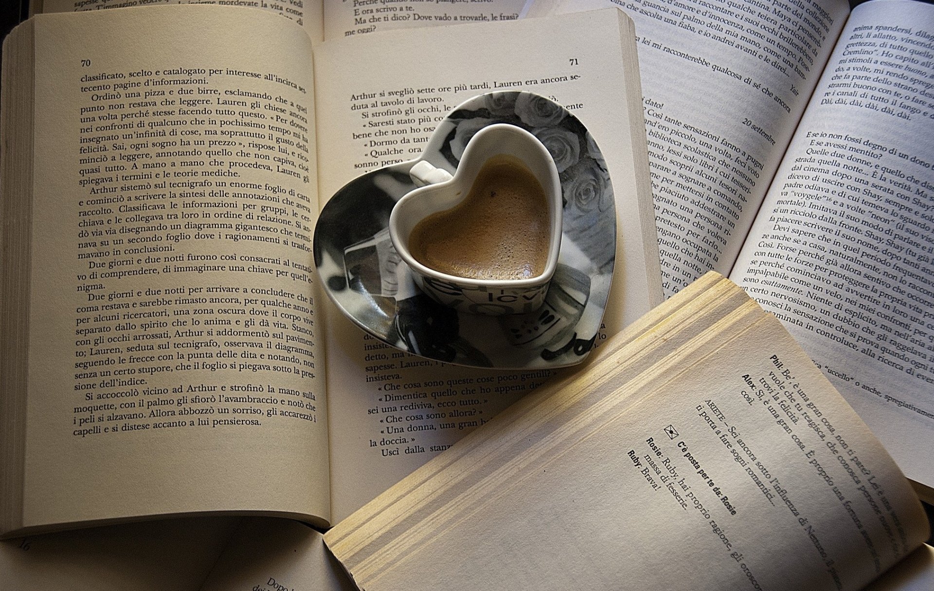 A cozy scene featuring a heart-shaped coffee cup placed on open books, creating an inviting atmosphere for relaxation and contemplation. HD PC desktop wallpaper.