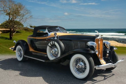 HD PC desktop wallpaper background: vintage Auburn convertible vehicle with whitewall tires parked on a coastal road under a blue sky
