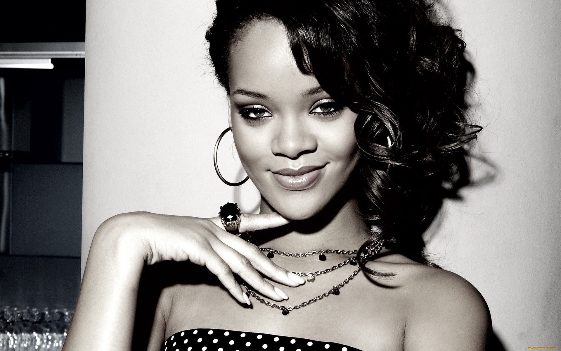 HD PC desktop wallpaper of a glamorous female music artist in black-and-white, smiling with hoop earrings and layered necklaces, striking a confident pose against a soft background.
