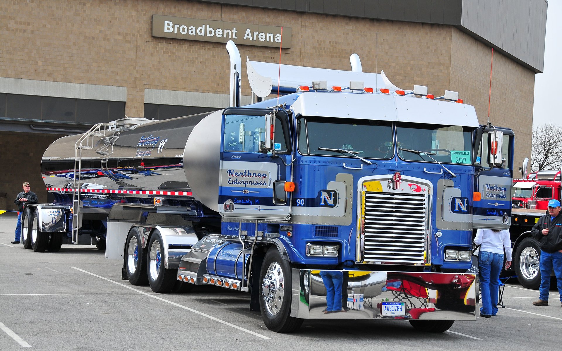HD desktop wallpaper featuring a blue Kenworth tanker truck parked near Broadbent Arena, showcasing its detailed design and polished chrome elements.