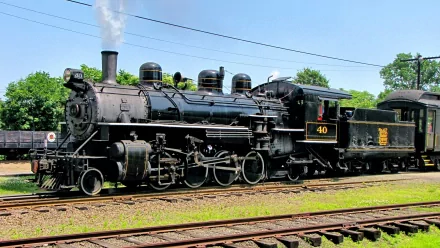 HD PC desktop wallpaper of a black vintage steam locomotive No. 40 resting on sunlit tracks with green trees and a clear blue sky background.
