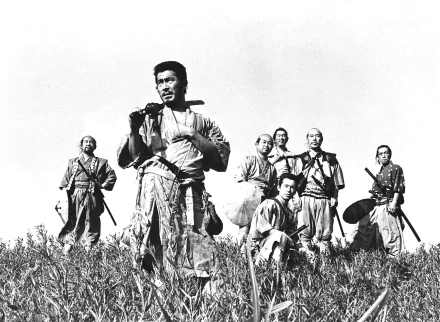 Black-and-white still from the movie Seven Samurai: seven samurai posed in a field with their leader in the foreground — HD PC desktop wallpaper and background.