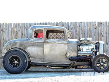 HD desktop wallpaper of a classic 1932 Ford Deuce Coupe hot rod parked in front of a wooden fence, showcasing its polished engine and vintage design.