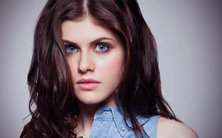 HD desktop wallpaper featuring celebrity Alexandra Daddario with striking blue eyes and dark wavy hair, wearing a blue shirt.