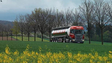 A Scania truck drives through a vibrant green field, framed by rows of trees and a backdrop of a cloudy sky, creating a striking HD desktop wallpaper.