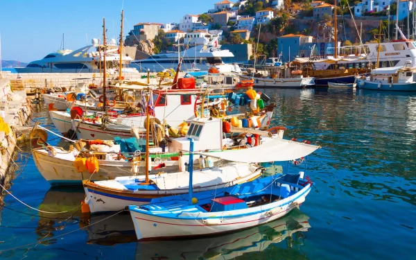 HD PC desktop wallpaper showing colorful boats docked in a vibrant coastal harbor with houses on the hillside in bright sunlight.