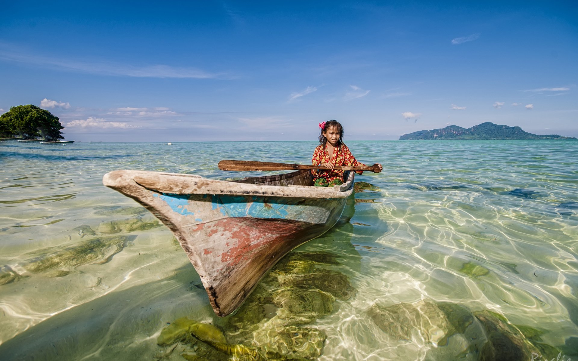 HD PC desktop wallpaper/background: a small wooden canoe vehicle with a person aboard drifting in crystal-clear shallow sea under a bright blue sky.