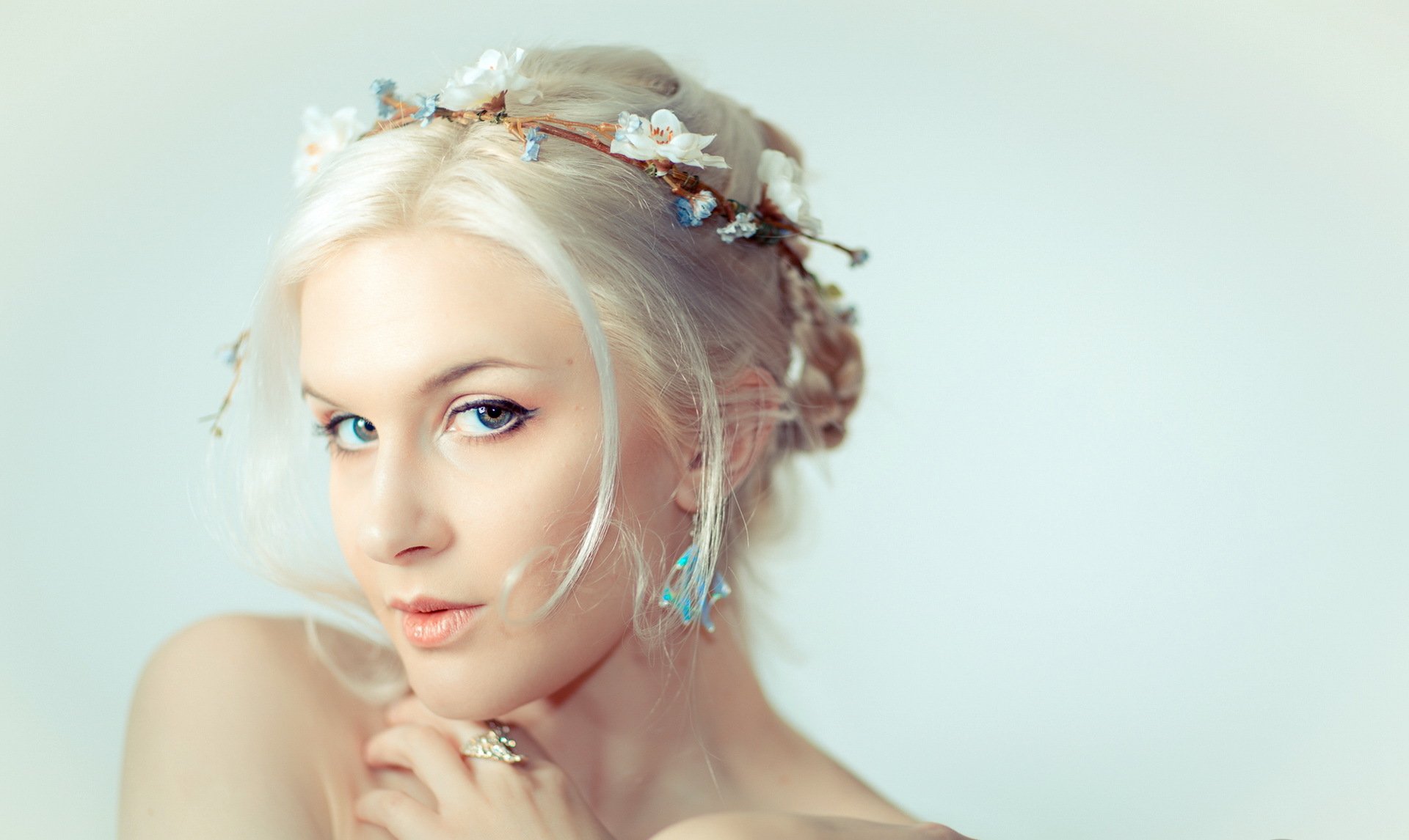 A woman with light blonde hair adorned with a floral crown gazes intently at the viewer, creating a serene and captivating presence in this HD desktop wallpaper.