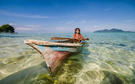 HD PC desktop wallpaper/background: a small wooden canoe vehicle with a person aboard drifting in crystal-clear shallow sea under a bright blue sky.
