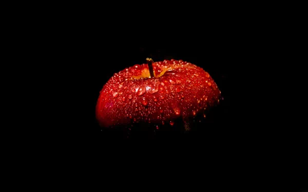 A close-up of a freshly washed red apple covered in droplets, set against a dark background, creating a striking and vibrant HD desktop wallpaper.