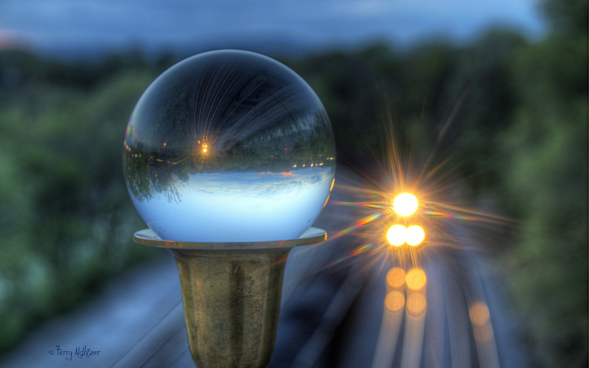 HD photography wallpaper featuring a glowing crystal ball reflecting a sunset over blurred train tracks and approaching headlights in a serene outdoor setting.