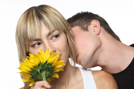 A romantic close-up photograph of a man whispering to a woman holding a vibrant yellow sunflower, captured in 4K Ultra HD for a striking PC desktop wallpaper.