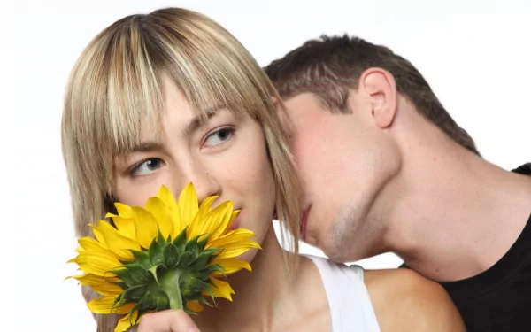 A romantic close-up photograph of a man whispering to a woman holding a vibrant yellow sunflower, captured in 4K Ultra HD for a striking PC desktop wallpaper.
